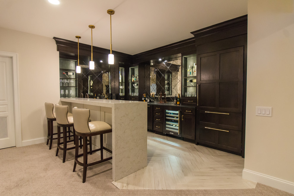 Large modern seated home bar in DC Metro with an undermount sink, dark wood cabinets, marble benchtops, glass tile splashback, porcelain floors, white floor and beige benchtop.