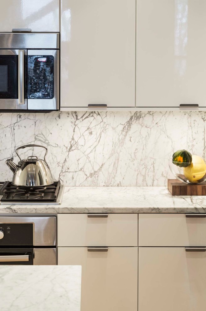 Inspiration for a small modern u-shaped eat-in kitchen in New York with an undermount sink, flat-panel cabinets, white cabinets, marble benchtops, white splashback, marble splashback, stainless steel appliances, light hardwood floors, a peninsula and yellow floor.