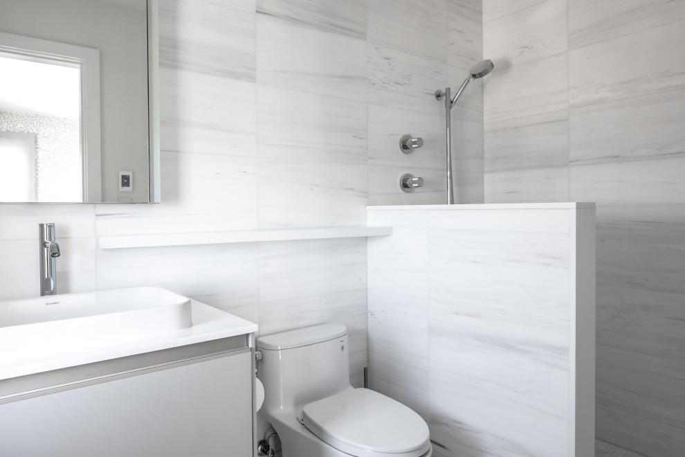This is an example of a medium sized modern shower room bathroom in New York with flat-panel cabinets, a walk-in shower, a one-piece toilet, a vessel sink, engineered stone worktops, an open shower, white worktops, grey cabinets, a single sink and grey tiles.