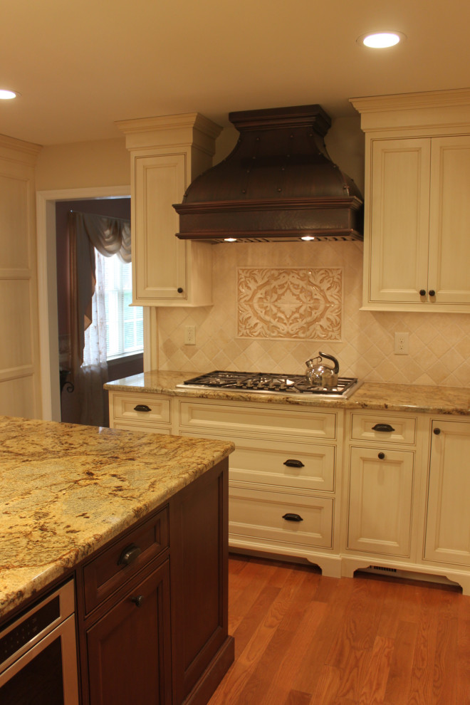 Large elegant medium tone wood floor kitchen photo with beaded inset cabinets, granite countertops, beige backsplash, stone tile backsplash, stainless steel appliances and an island