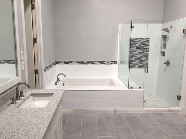 Inspiration for a mid-sized modern master bathroom in Dallas with shaker cabinets, a drop-in tub, a corner shower, matchstick tile, grey walls, porcelain floors, an undermount sink, granite benchtops and a hinged shower door.
