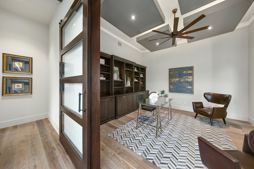 Photo of a mid-sized transitional home office in Austin with a library, white walls, porcelain floors, no fireplace, a freestanding desk and brown floor.