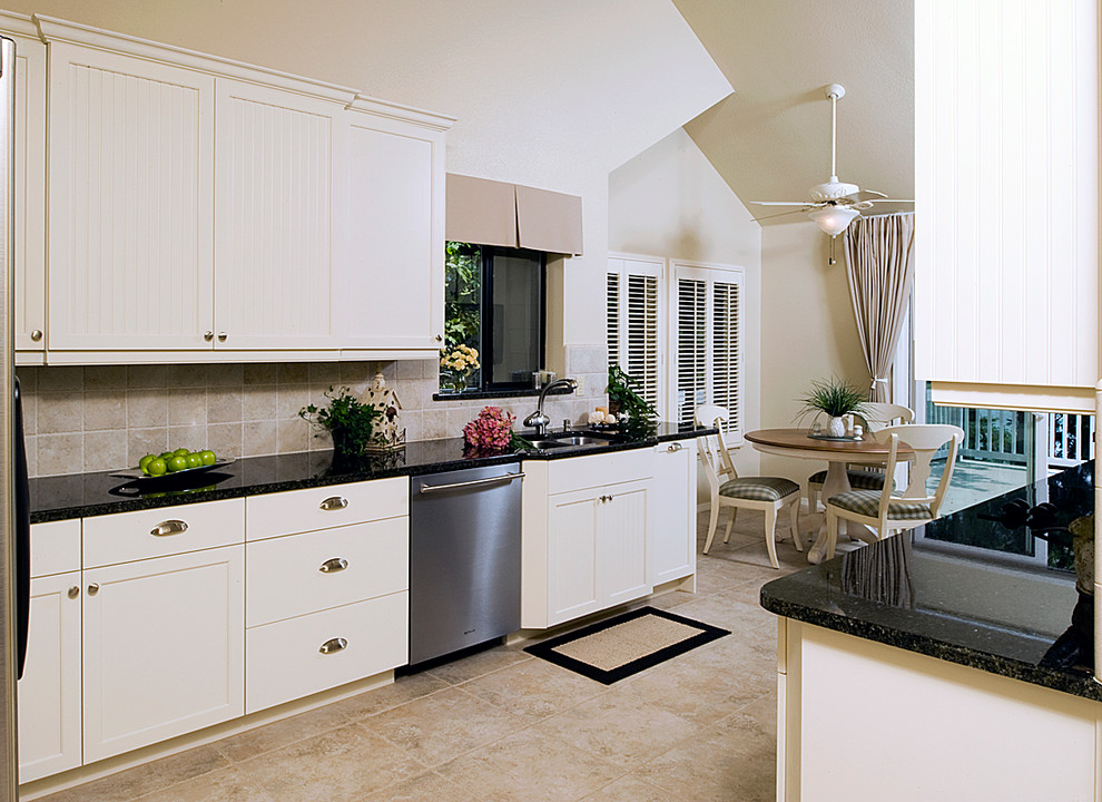 Eat-in kitchen - mid-sized transitional galley porcelain tile eat-in kitchen idea with shaker cabinets, white cabinets, granite countertops, beige backsplash, porcelain backsplash and stainless steel appliances