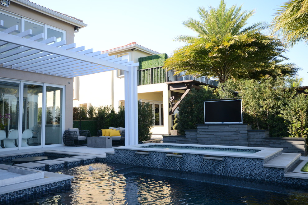 Photo of an expansive contemporary backyard patio in Miami with an outdoor kitchen, decking and a pergola.
