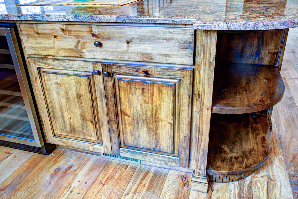 Kitchen pantry - large rustic u-shaped medium tone wood floor kitchen pantry idea with a drop-in sink, glass-front cabinets, medium tone wood cabinets, beige backsplash, stainless steel appliances and an island
