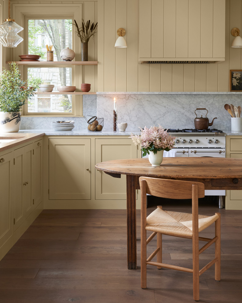 Inspiration for a medium sized classic kitchen/diner in Columbus with shaker cabinets, yellow cabinets, marble worktops, grey splashback, marble splashback, white appliances, medium hardwood flooring, no island, brown floors and grey worktops.