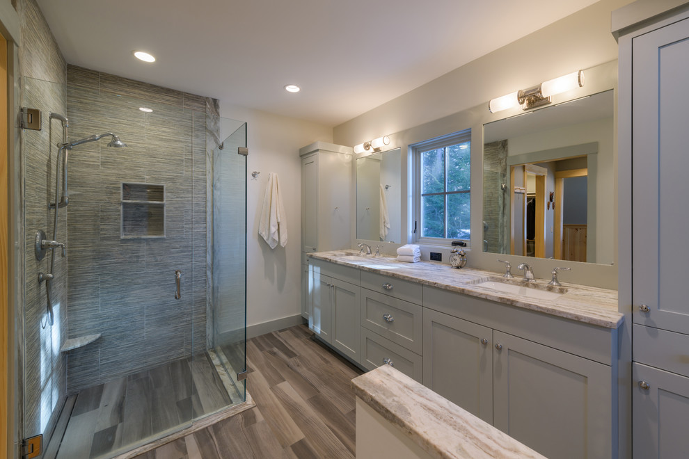 Walk-in shower - transitional master gray tile medium tone wood floor and brown floor walk-in shower idea in Boston with shaker cabinets, gray cabinets, white walls, an undermount sink, a hinged shower door and beige countertops
