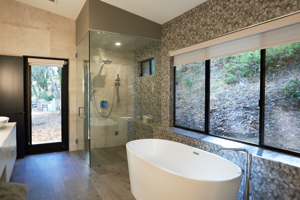 This is an example of a mid-sized contemporary master bathroom in San Francisco with flat-panel cabinets, white cabinets, a freestanding tub, a wall-mount toilet, green tile, porcelain tile, green walls, light hardwood floors, a vessel sink, marble benchtops, yellow benchtops, a corner shower, beige floor and a hinged shower door.