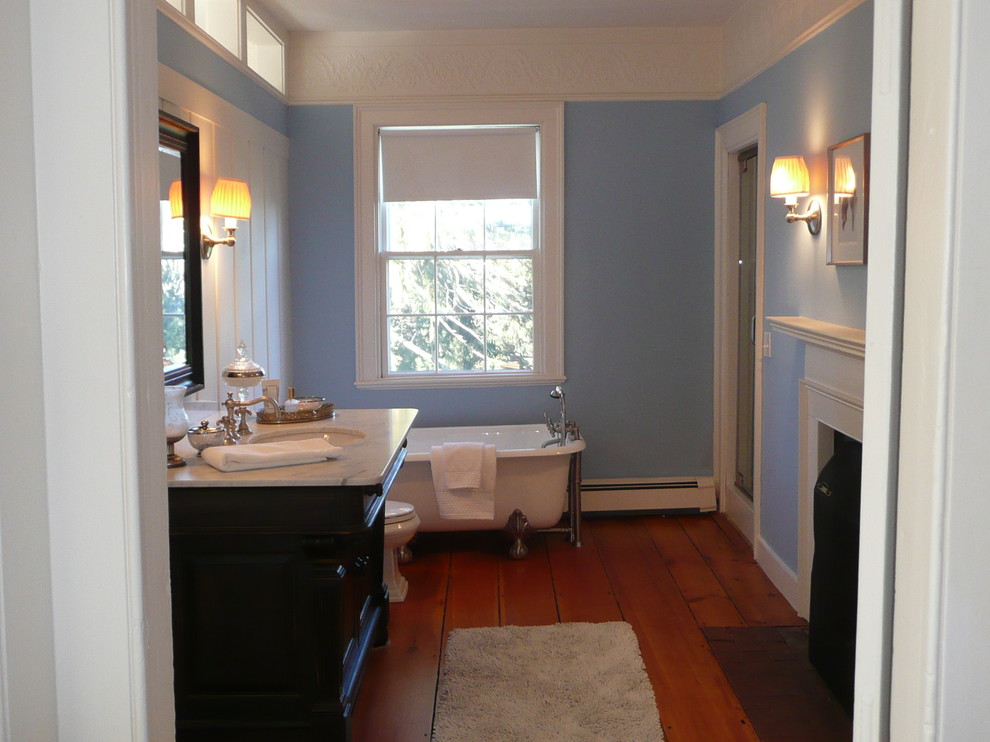 This is an example of a mid-sized traditional master bathroom in Boston with an undermount sink, furniture-like cabinets, black cabinets, marble benchtops, a claw-foot tub, a one-piece toilet, blue walls and medium hardwood floors.