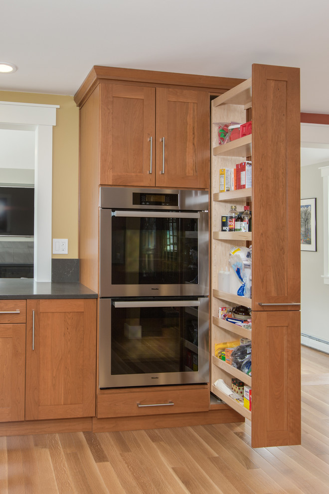 Transitional u-shaped medium tone wood floor kitchen photo in Boston with an undermount sink, shaker cabinets, medium tone wood cabinets, quartz countertops, gray backsplash, stone slab backsplash, stainless steel appliances and an island