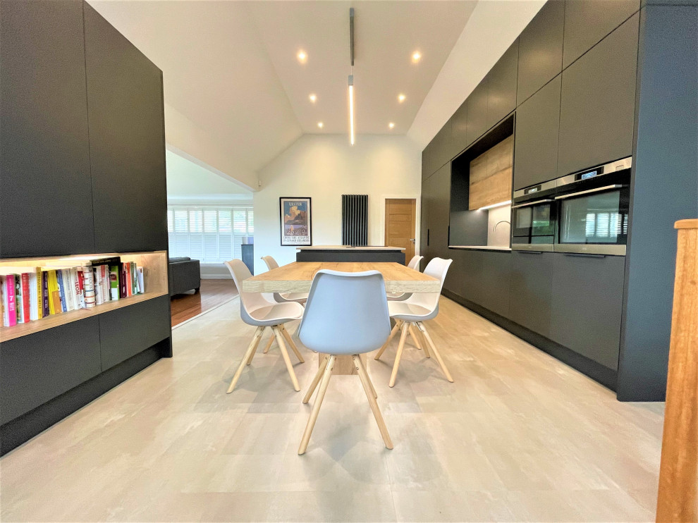 Photo of a large contemporary single-wall open plan kitchen in Other with a double-bowl sink, flat-panel cabinets, light wood cabinets, solid surface benchtops, grey splashback, black appliances, vinyl floors, with island, grey floor, grey benchtop and vaulted.