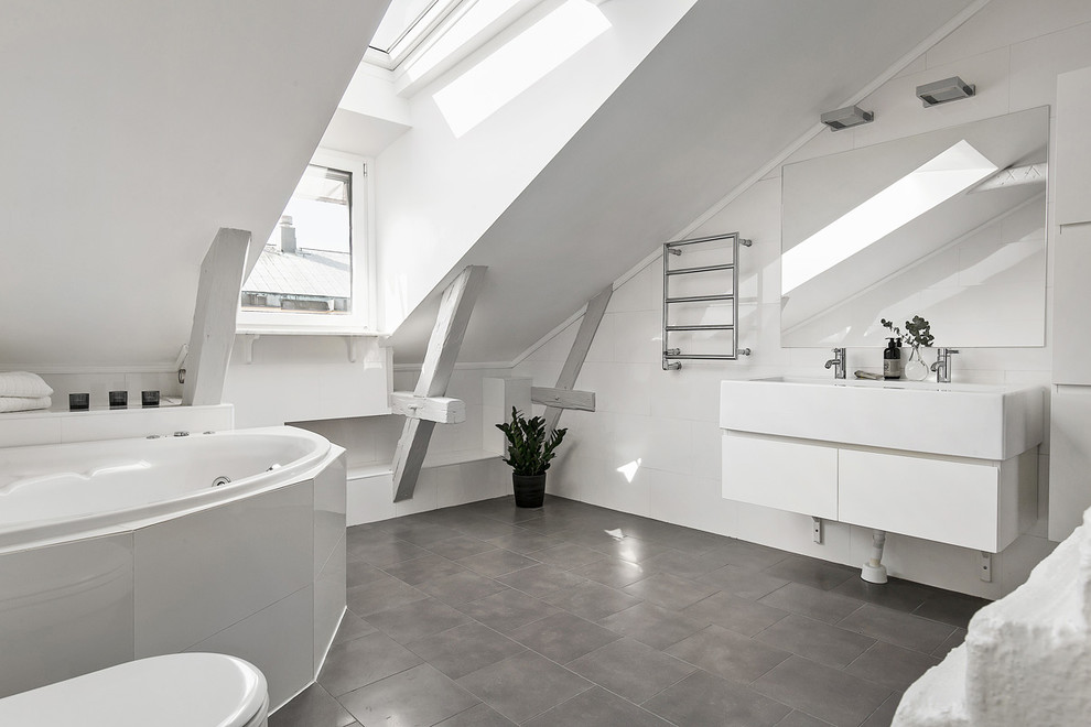 Photo of a large scandinavian bathroom in Stockholm with flat-panel cabinets, white cabinets, a corner tub, white walls, ceramic floors and an integrated sink.
