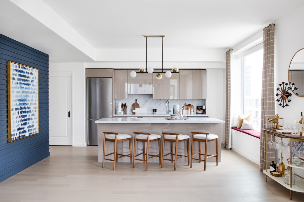 Photo of a large midcentury single-wall open plan kitchen in Los Angeles with flat-panel cabinets, beige cabinets, grey splashback, marble splashback, stainless steel appliances, light hardwood floors, with island, an undermount sink, marble benchtops and beige floor.