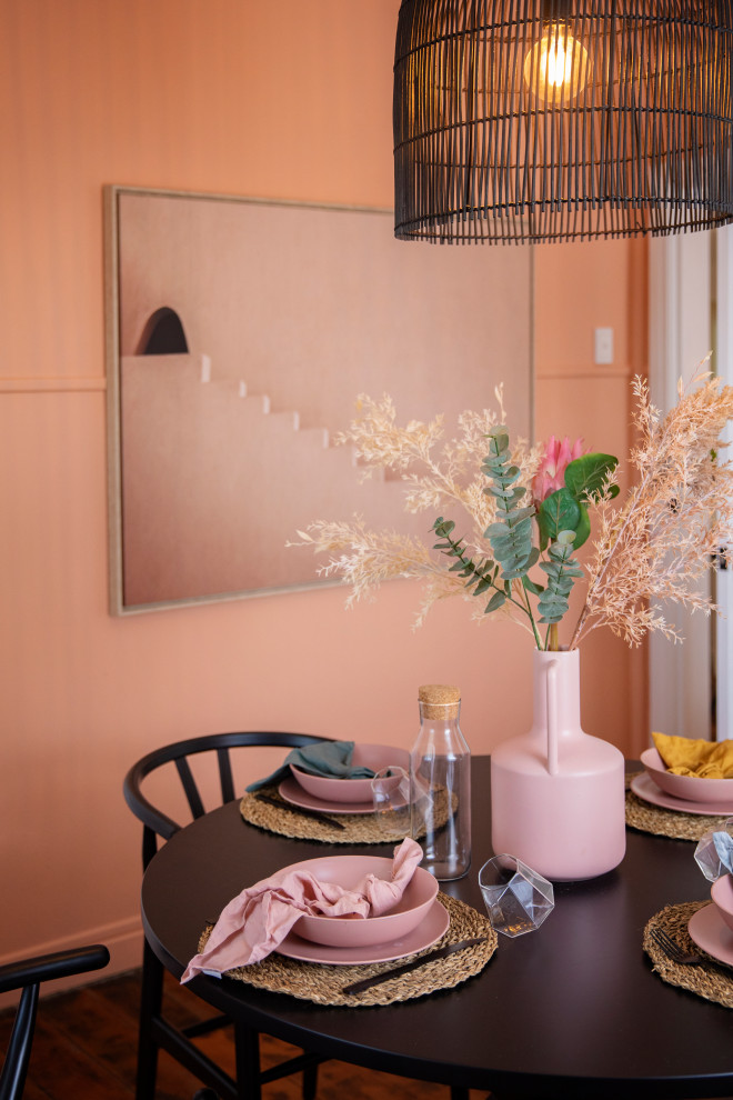 Cette image montre une salle à manger méditerranéenne fermée et de taille moyenne avec un mur rose, parquet foncé et un sol marron.