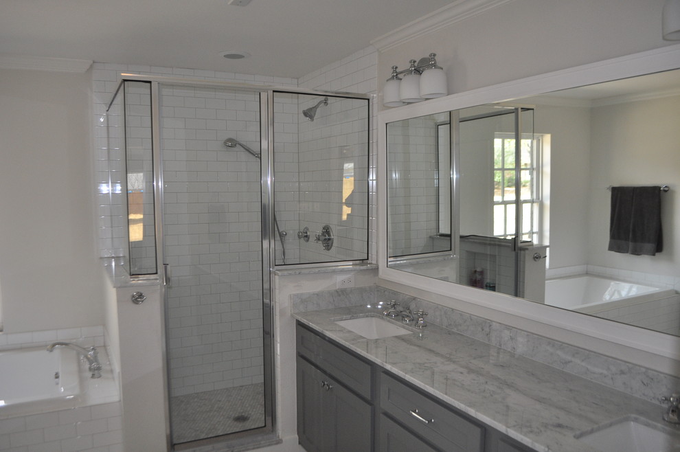 This is an example of a traditional master bathroom in Dallas with shaker cabinets, grey cabinets, a drop-in tub, a corner shower, a two-piece toilet, white tile, ceramic tile, grey walls, marble floors and an undermount sink.
