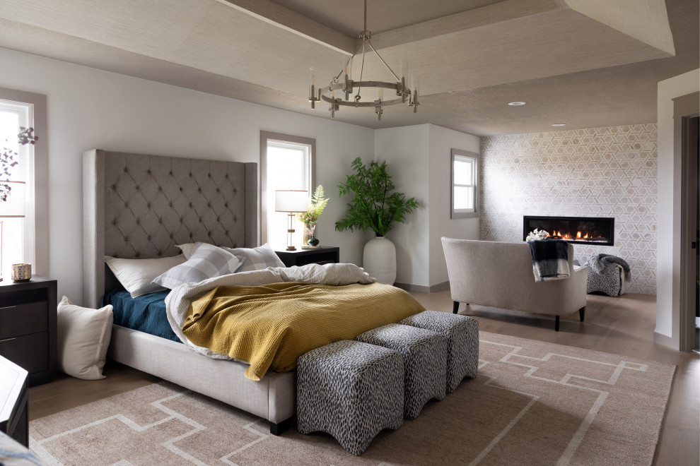 Photo of a classic master bedroom in Kansas City with white walls, light hardwood flooring, a standard fireplace, a tiled fireplace surround, beige floors and a drop ceiling.