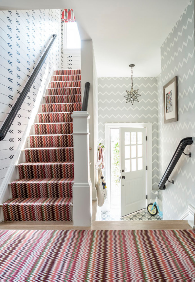 This is an example of a coastal staircase in New York with wallpapered walls.
