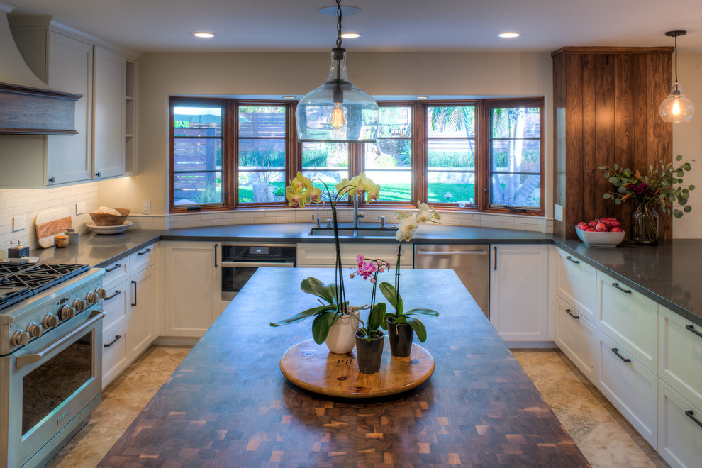 This is an example of a mid-sized country u-shaped open plan kitchen in Denver with an undermount sink, recessed-panel cabinets, white cabinets, quartzite benchtops, white splashback, subway tile splashback, stainless steel appliances, travertine floors, with island and beige floor.