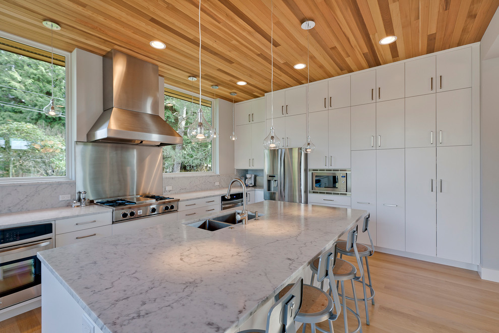 Transitional medium tone wood floor kitchen photo in Seattle with an undermount sink, flat-panel cabinets, white cabinets, stainless steel appliances and an island