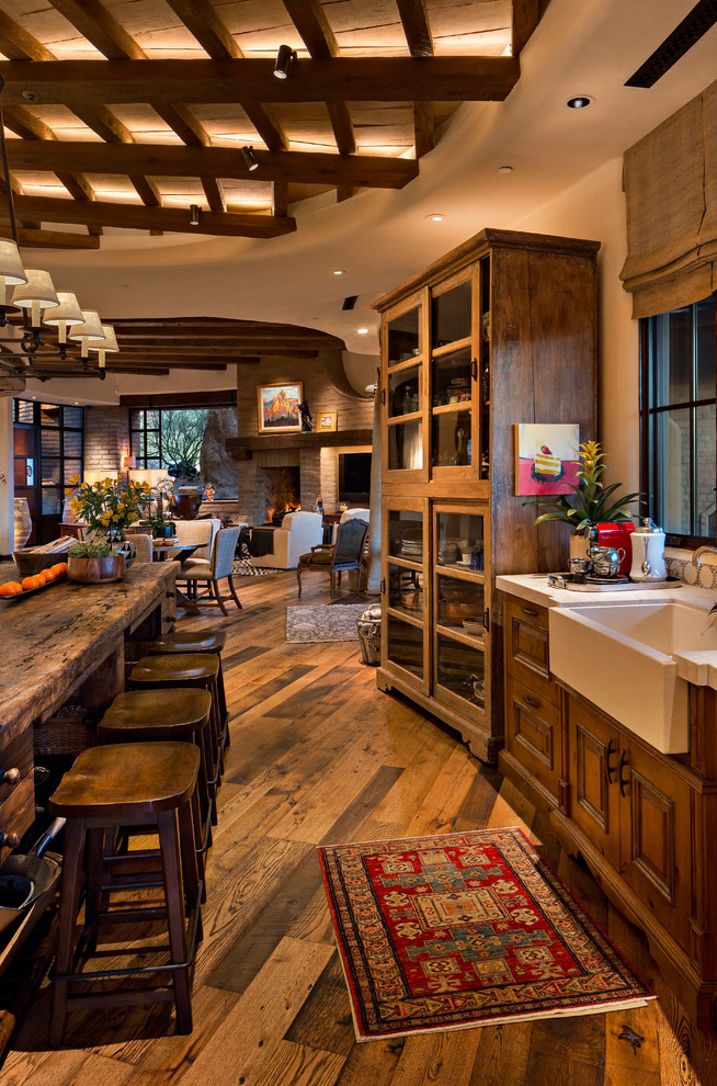 Inspiration for a large galley eat-in kitchen in Phoenix with a farmhouse sink, recessed-panel cabinets, medium wood cabinets, limestone benchtops, white splashback, mosaic tile splashback, stainless steel appliances, medium hardwood floors, with island and brown floor.