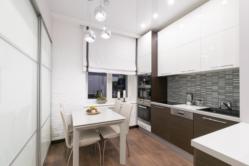 Design ideas for a contemporary l-shaped separate kitchen in Moscow with a drop-in sink, flat-panel cabinets, white cabinets, grey splashback, stainless steel appliances, no island, brown floor and white benchtop.