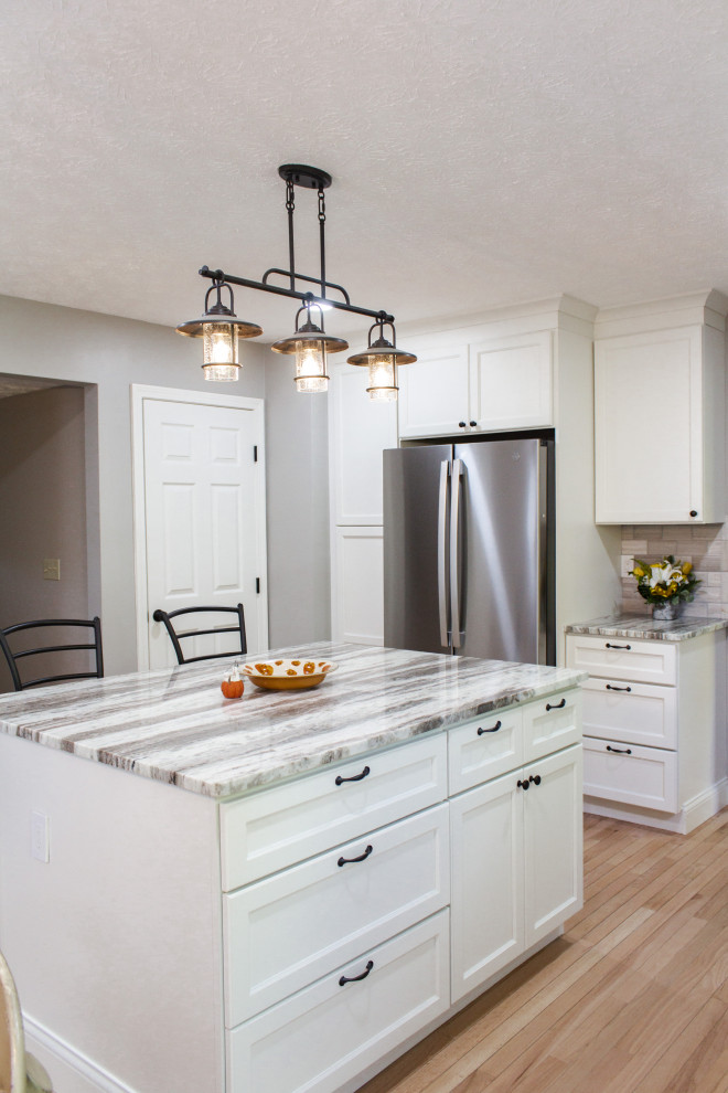 Inspiration for a transitional l-shaped light wood floor and beige floor kitchen remodel in Columbus with an undermount sink, white cabinets, gray backsplash, an island and gray countertops