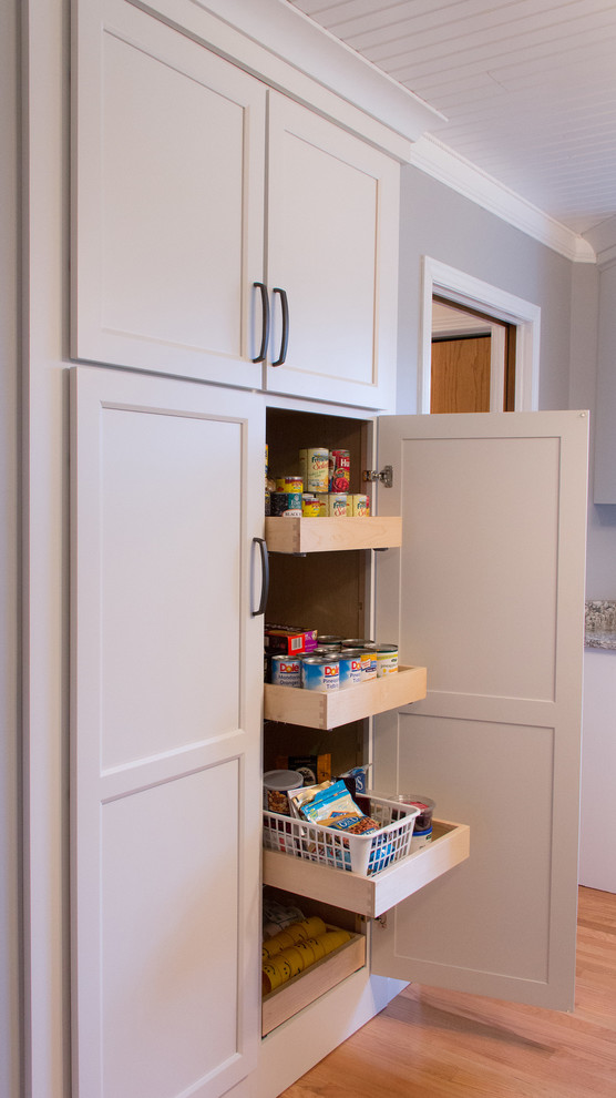Inspiration for a mid-sized transitional u-shaped medium tone wood floor enclosed kitchen remodel with an undermount sink, recessed-panel cabinets, white cabinets, quartz countertops, stainless steel appliances and an island