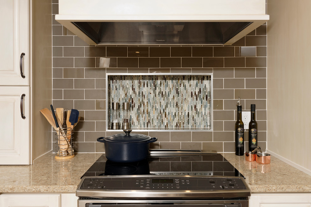Eat-in kitchen - large transitional l-shaped ceramic tile eat-in kitchen idea in DC Metro with raised-panel cabinets, white cabinets, glass tile backsplash, stainless steel appliances, an island, an undermount sink, quartz countertops and beige backsplash