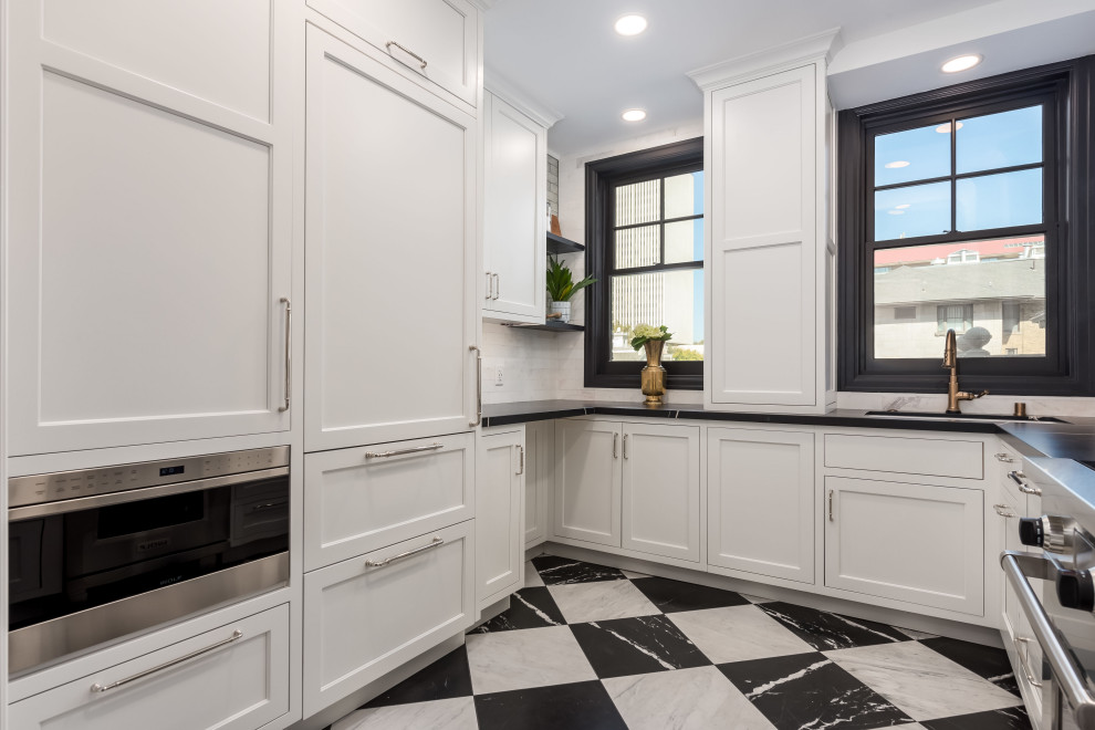 This is an example of a small transitional u-shaped kitchen in Salt Lake City with an undermount sink, beaded inset cabinets, white cabinets, quartz benchtops, white splashback, marble splashback, panelled appliances, marble floors, no island, multi-coloured floor and black benchtop.