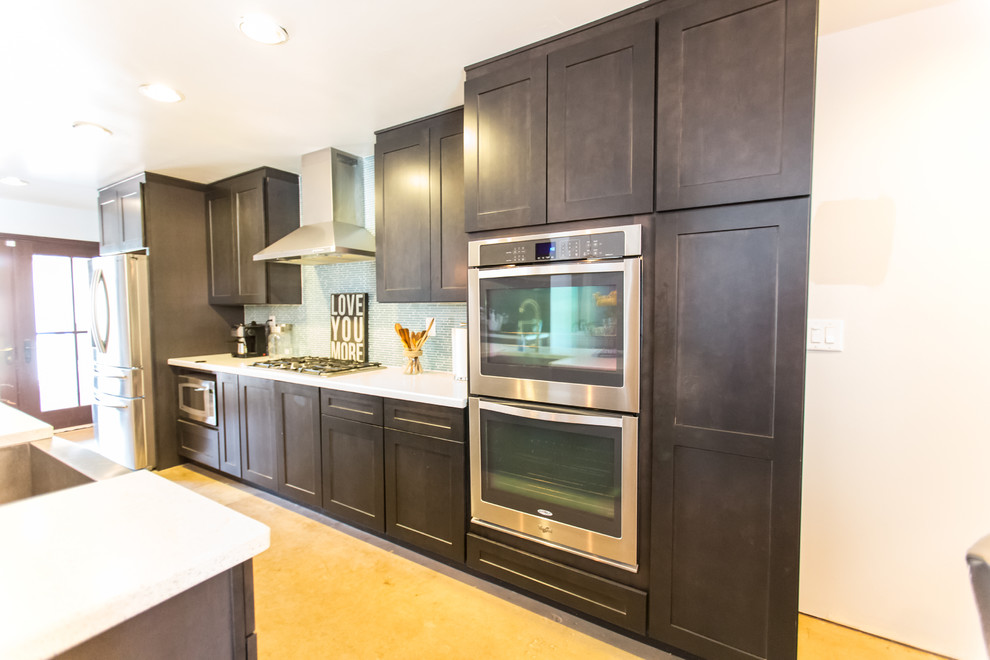 Inspiration for a mid-sized rustic single-wall concrete floor and gray floor open concept kitchen remodel in Phoenix with dark wood cabinets, blue backsplash, stainless steel appliances, an island, an undermount sink, shaker cabinets, quartzite countertops and glass tile backsplash