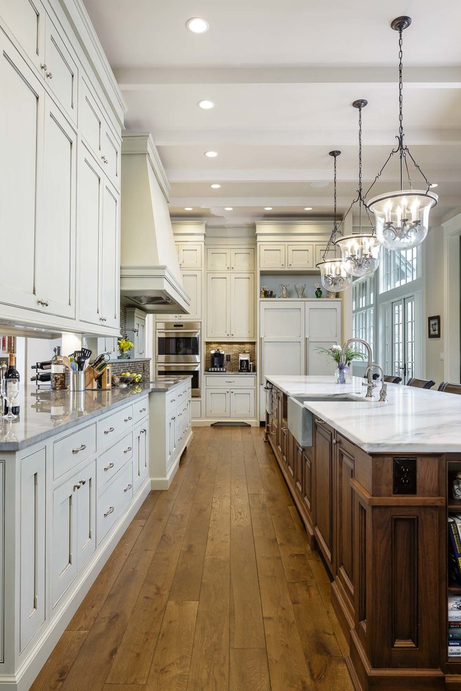 Photo of an expansive traditional l-shaped open plan kitchen in Nashville with a farmhouse sink, flat-panel cabinets, green cabinets, marble benchtops, brown splashback, panelled appliances, medium hardwood floors and with island.