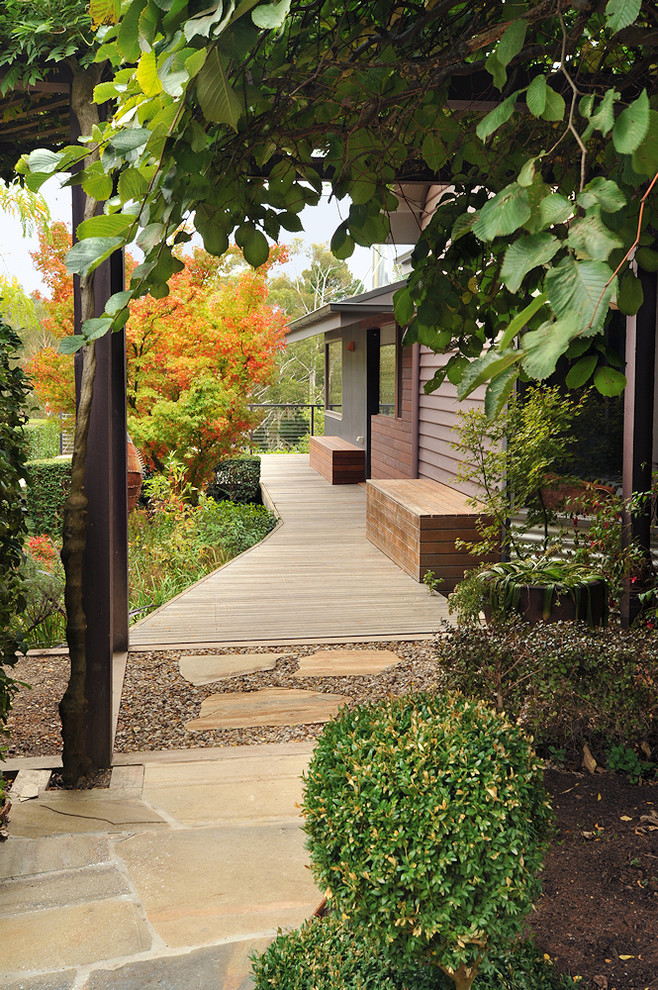 Eclectic front yard shaded garden in Melbourne with a garden path and natural stone pavers for fall.