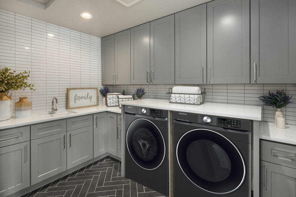 This is an example of a large contemporary l-shaped laundry room in Other with an undermount sink, flat-panel cabinets, grey cabinets, marble benchtops, white benchtop, grey splashback, mosaic tile splashback, marble floors, a side-by-side washer and dryer and black floor.