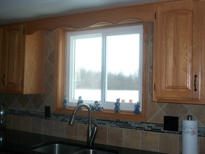 Example of a transitional kitchen design with a double-bowl sink, light wood cabinets, beige backsplash, matchstick tile backsplash, stainless steel appliances and no island