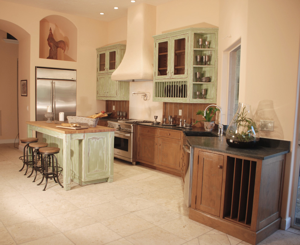 Large mountain style u-shaped ceramic tile and beige floor enclosed kitchen photo in Miami with a farmhouse sink, beaded inset cabinets, green cabinets, solid surface countertops, brown backsplash, wood backsplash, stainless steel appliances and an island