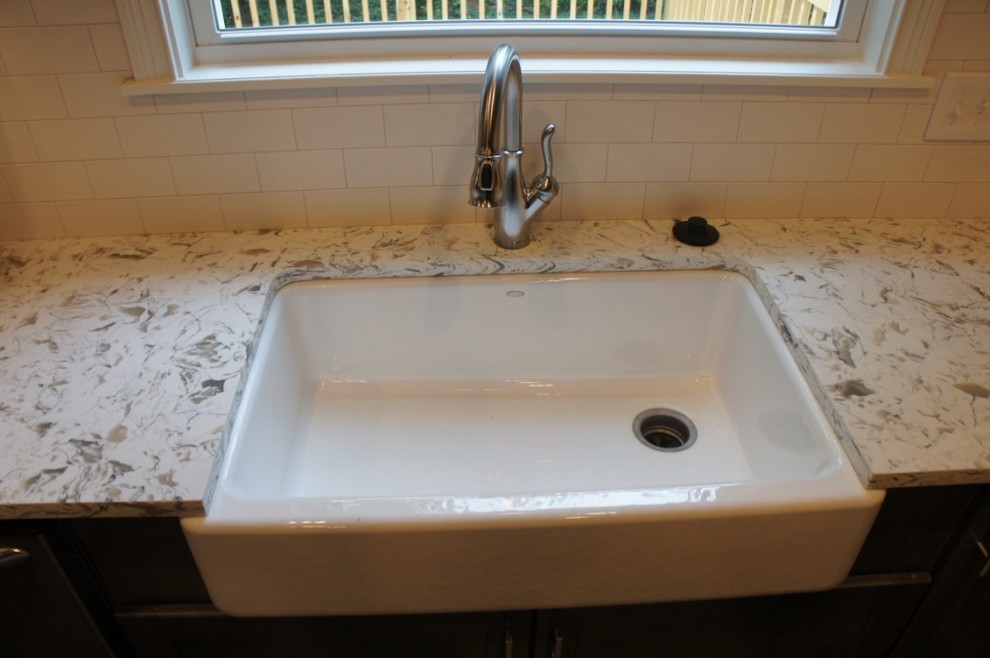 Transitional u-shaped eat-in kitchen photo with a farmhouse sink, flat-panel cabinets, white backsplash, ceramic backsplash, stainless steel appliances and an island