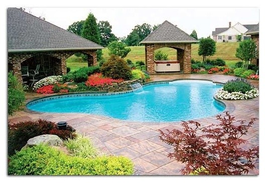 Backyard stone and custom-shaped pool photo