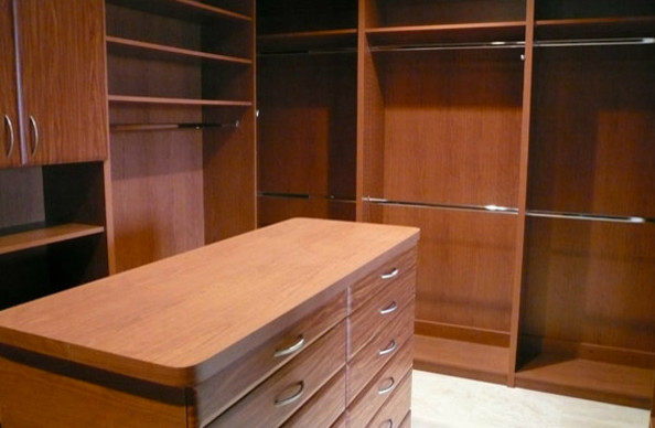 This is an example of a mid-sized contemporary gender-neutral walk-in wardrobe in Other with flat-panel cabinets, medium wood cabinets, carpet and beige floor.