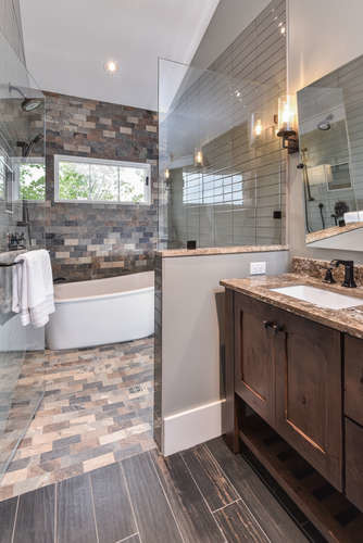 This is an example of a mid-sized arts and crafts master bathroom in Other with furniture-like cabinets, medium wood cabinets, a freestanding tub, an open shower, brown tile, stone tile, grey walls, porcelain floors, an undermount sink, granite benchtops, brown floor and a hinged shower door.