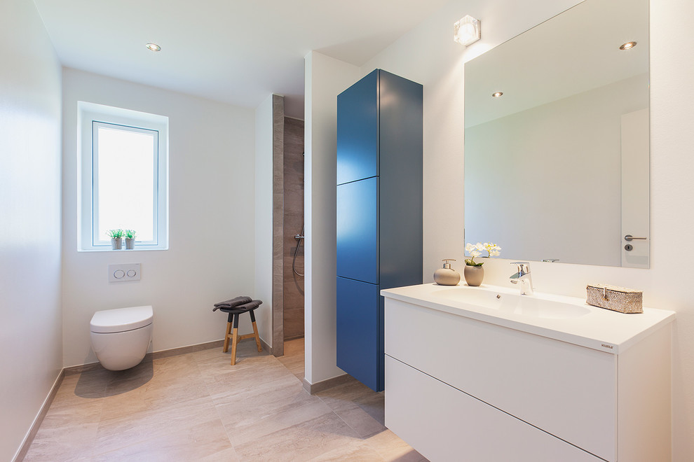 Photo of a large scandinavian 3/4 bathroom in Copenhagen with an integrated sink, flat-panel cabinets, a curbless shower, a wall-mount toilet, white cabinets, white walls, concrete floors and laminate benchtops.