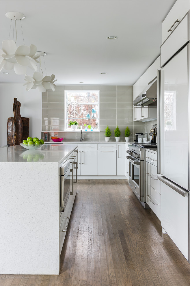 Large contemporary l-shaped eat-in kitchen in New York with an undermount sink, flat-panel cabinets, white cabinets, quartz benchtops, grey splashback, glass tile splashback, panelled appliances, dark hardwood floors and with island.