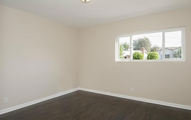 This is an example of a mid-sized transitional guest bedroom in Los Angeles with beige walls and dark hardwood floors.