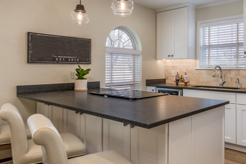 Transitional galley vinyl floor and beige floor eat-in kitchen photo with a double-bowl sink, recessed-panel cabinets, white cabinets, granite countertops, beige backsplash, travertine backsplash, stainless steel appliances, a peninsula and black countertops