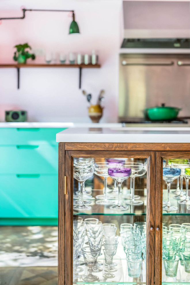 Design ideas for a mid-sized eclectic single-wall eat-in kitchen in London with flat-panel cabinets, green cabinets, solid surface benchtops, with island and white benchtop.