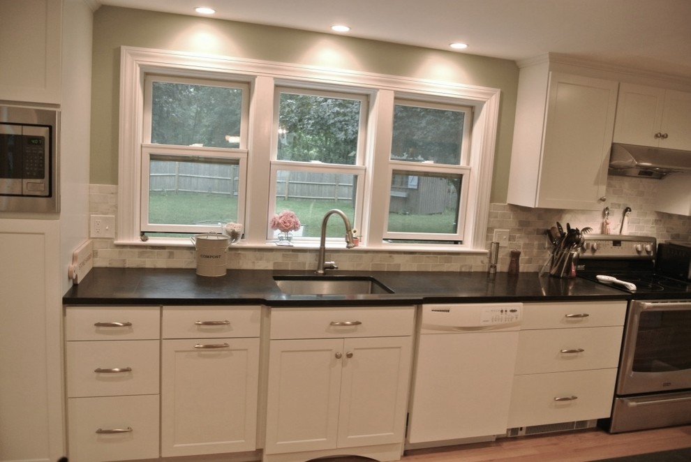Eat-in kitchen - transitional u-shaped light wood floor eat-in kitchen idea in Boston with an undermount sink, shaker cabinets, white cabinets, beige backsplash, porcelain backsplash, stainless steel appliances, a peninsula and black countertops