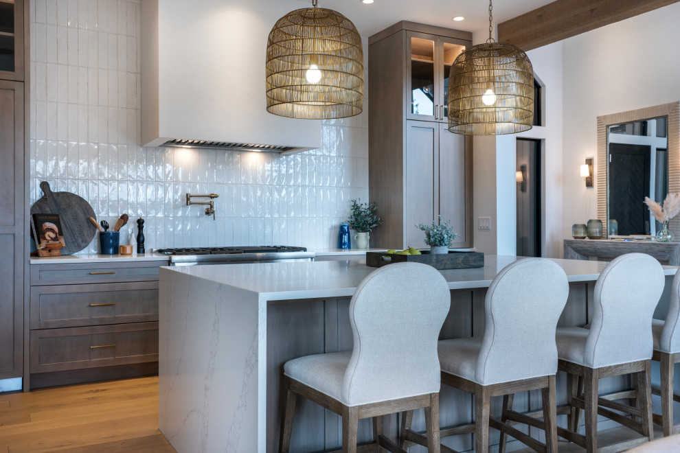 Inspiration for a large transitional l-shaped light wood floor and exposed beam open concept kitchen remodel with a farmhouse sink, shaker cabinets, medium tone wood cabinets, quartz countertops, white backsplash, subway tile backsplash, stainless steel appliances, an island and white countertops