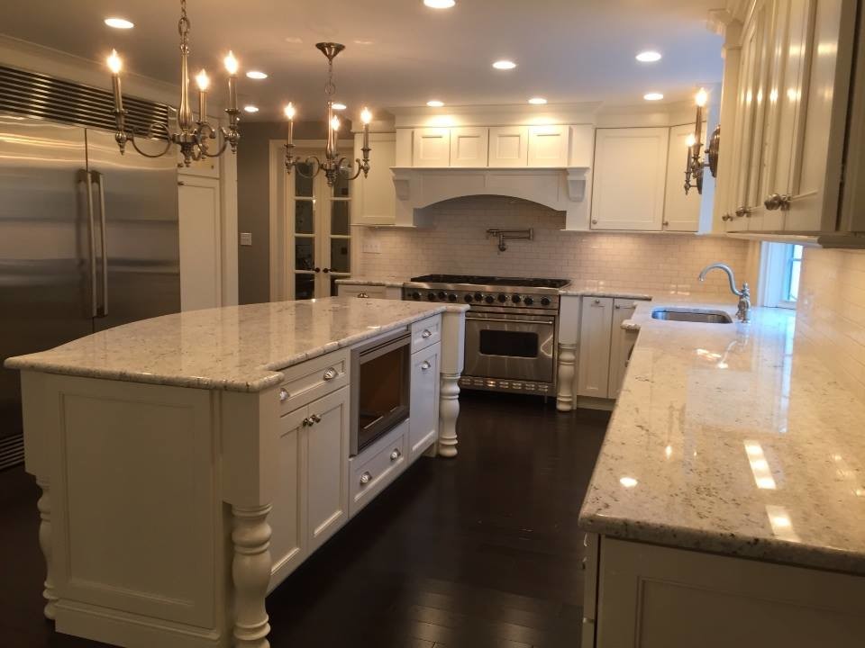 Example of a transitional u-shaped dark wood floor kitchen design in New York with an undermount sink, recessed-panel cabinets, white cabinets, granite countertops, white backsplash, subway tile backsplash, stainless steel appliances and an island