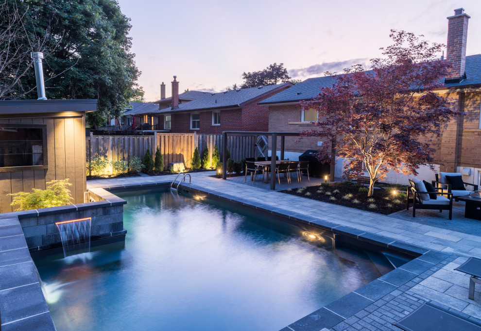 Example of a mid-sized transitional backyard concrete paver and l-shaped lap pool fountain design in Toronto