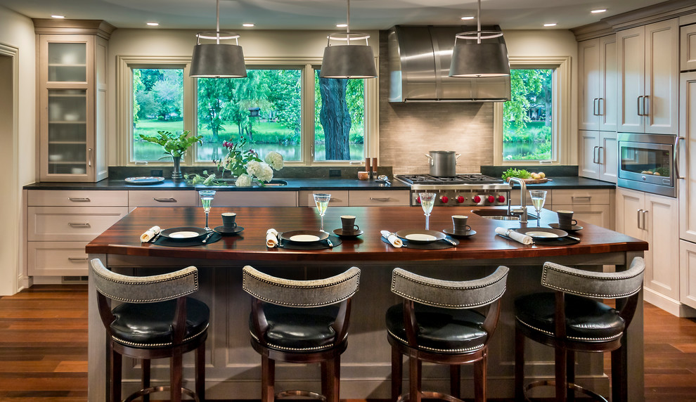 Photo of a large transitional l-shaped eat-in kitchen in Chicago with an undermount sink, flat-panel cabinets, grey cabinets, granite benchtops, grey splashback, stone tile splashback, panelled appliances, medium hardwood floors and with island.
