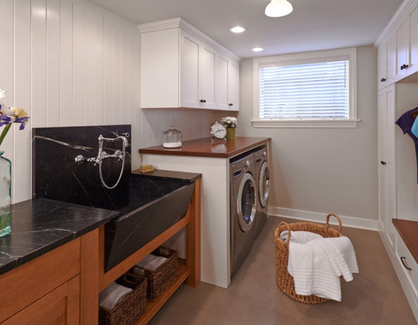 This is an example of a modern utility room in Seattle with a farmhouse sink, wood benchtops, white walls and a side-by-side washer and dryer.